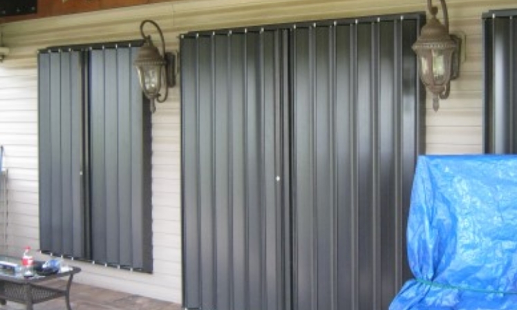 bronze accordion hurricane shutters and impact windows closed protecting home from storms